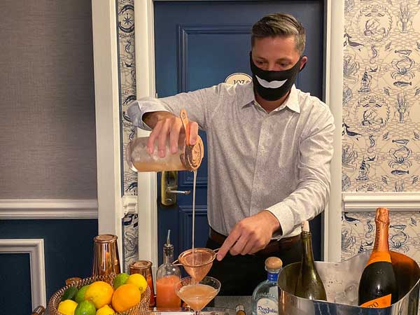 Bartender In A Mask Pouring A Drink For Room Service.