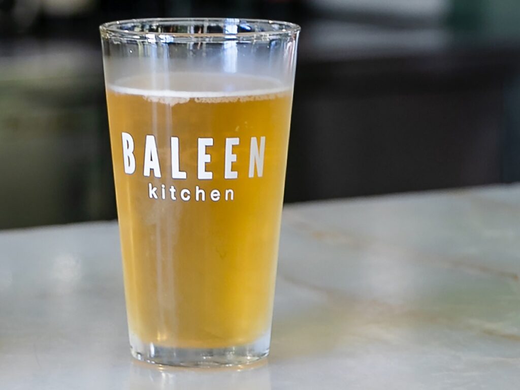 Chilled craft beer in a branded Baleen Kitchen pint glass on a marble bar at The Portofino Hotel & Marina in Redondo Beach, California