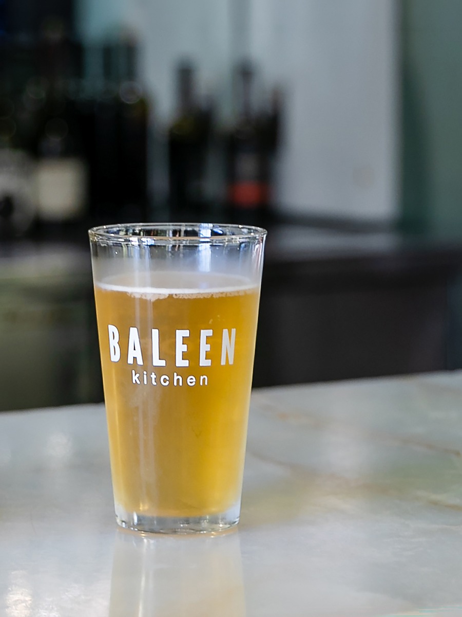 Chilled craft beer in a branded Baleen Kitchen pint glass on a marble bar at The Portofino Hotel & Marina in Redondo Beach, California