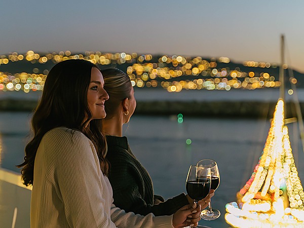 Two friends with red wine watching a lit sailboat on the water at dusk from The Portofino Hotel & Marina in King Harbor, Redondo Beach