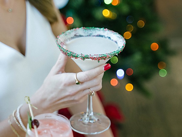 Woman holding a sugar-rimmed holiday martini beside a Christmas tree at A Coastal Christmas Bar, The Portofino Hotel & Marina in Redondo Beach