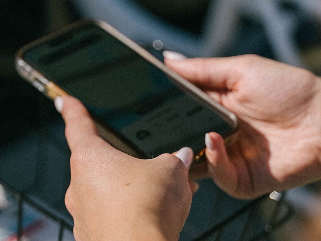 Guest using a smartphone to book a waterfront stay at The Portofino Hotel & Marina in Redondo Beach, California.