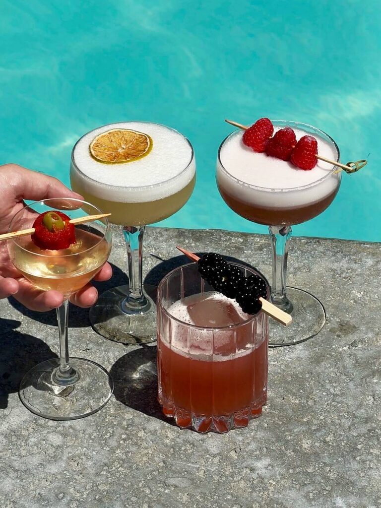 Craft cocktails with fresh berry and citrus garnishes served poolside at The Portofino Hotel & Marina in Redondo Beach, California, overlooking King Harbor.